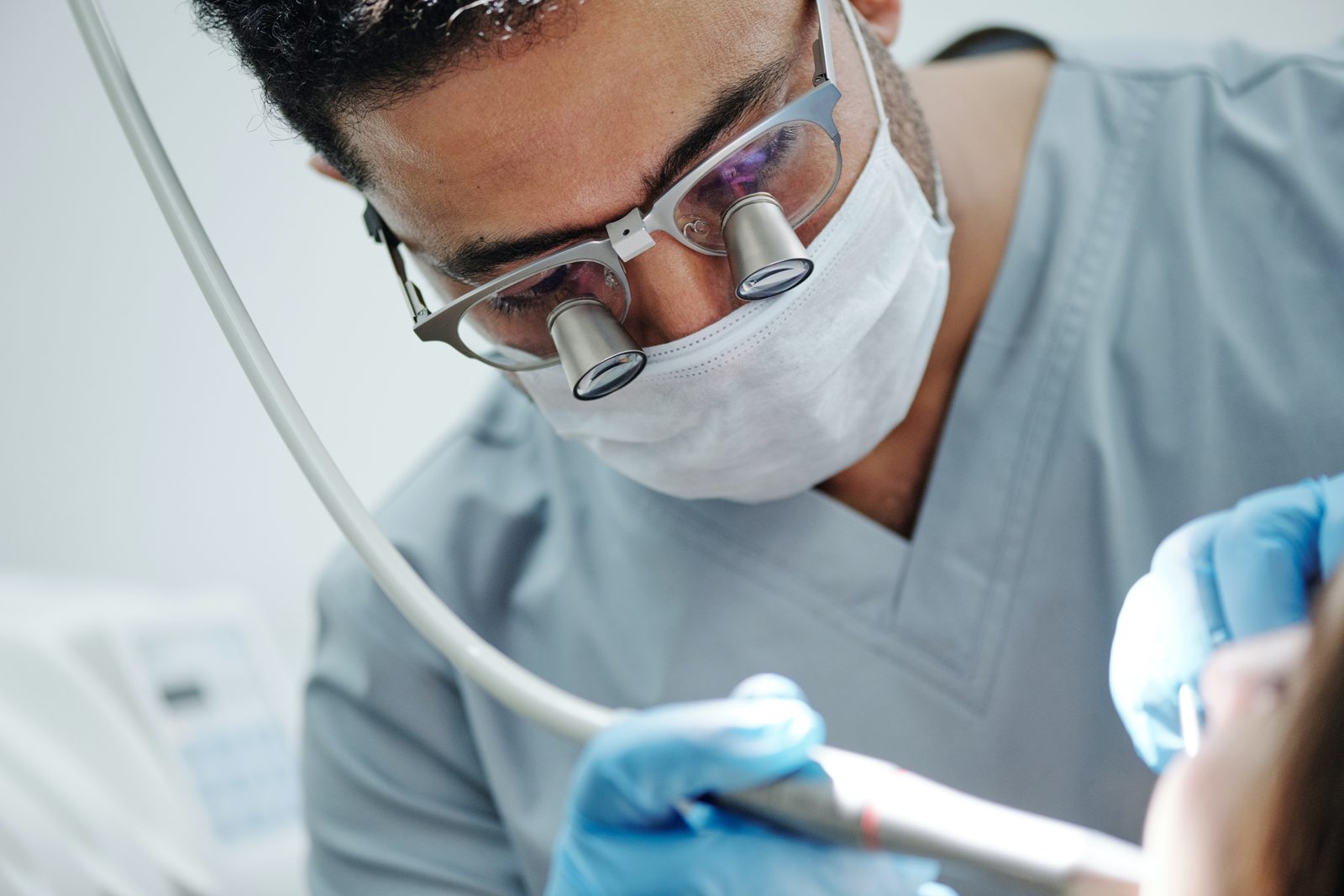Dentist wearing loupes and a mask while treating a patient